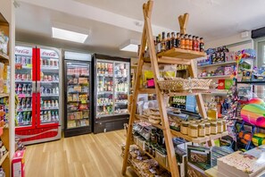 Un magasin doté de rayons réfrigérés, d’étagères remplies d’en-cas et d’un présentoir en bois où sont exposés divers articles.