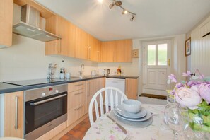 Una cocina moderna con armarios de madera, un horno Bosch y un comedor con mantel floral.