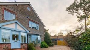 A two-story house with a stone facade, a blue front door, and a gravel driveway. - 3 Bed in Cley (oc-2122) (Cley next the Sea)