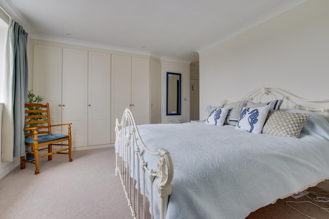 A bedroom with a bed, a chair, and a wardrobe.