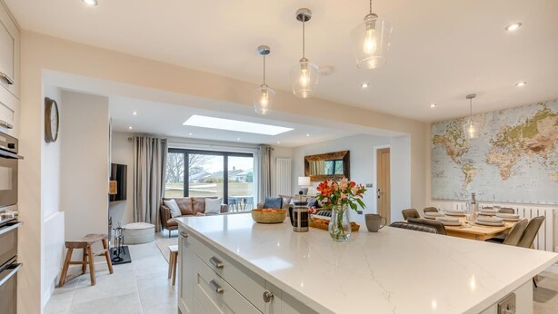 A modern kitchen with a large island, dining area, and a world map on the wall. - 3 Bed in Beadnell (oc-p32544) (Beadnell)