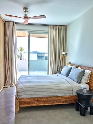 A bedroom with a wooden bed, a ceiling fan, and a view of a balcony. - Cala Conta 2 in Ibiza (Sant Josep de sa Talaia)
