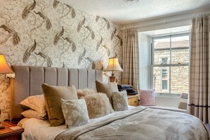 A bedroom with a large bed, two bedside lamps, a nightstand, and a window with curtains. - 3 Bed in Hawes (oc-ds1009) (Hawes)