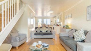 A spacious living room with two grey sofas, a glass coffee table, and a staircase. - 2 Bed in St. Issey (oc-a32428) (Saint Issey)
