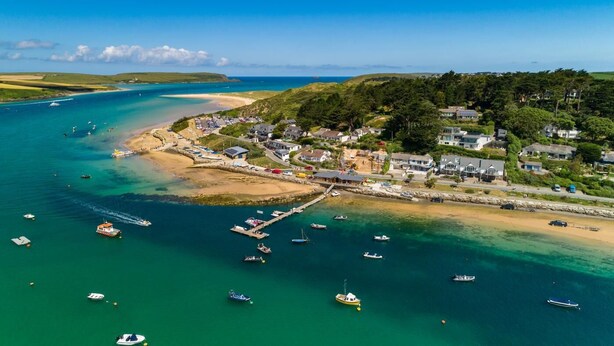 An aerial view of a coastal town with a marina, sandy beaches, and residential buildings. - 2 Bed in St. Issey (oc-a32428) (Saint Issey)