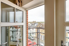A view from a balcony with a glass door, looking out onto a street with parked cars and residential buildings. - 3 Bed in Whitby (oc-w1003) (Whitby)