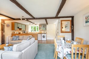 A cozy living room with a sofa, dining table, and chairs, a kitchen with a washing machine, and a dining area with a table set for two. - 2 Bed in Lyme Regis (oc-c32116) (Lyme Regis)