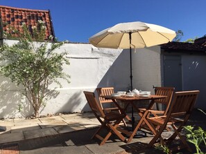 An outdoor patio with a round wooden table, four wooden chairs, a beige umbrella, and a small tree. - 2 Bed in Eye (oc-4lamb) (Eye)