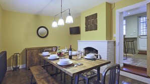 A dining area with a wooden table set for four, a fireplace, and a mirror on the wall. - 2 Bed in Eye (oc-4lamb) (Eye)