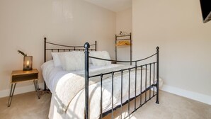 A bedroom with a metal-framed bed, a bedside table with a lamp, and a shelf with a hanging item. - 2 Bed in Eye (oc-4lamb) (Eye)