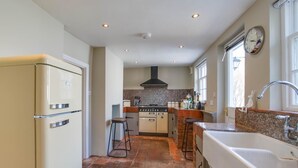A compact kitchen with a refrigerator, stove, sink, and stools. - 2 Bed in Eye (oc-4lamb) (Eye)