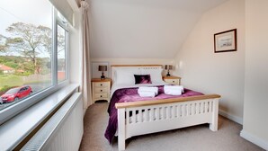 A bedroom with a bed, bedside tables, a window with a view of the outside, and a picture on the wall. - 3 Bed in Whitby (oc-w943) (Whitby)