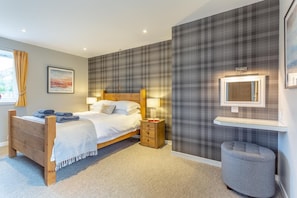 Ein Schlafzimmer mit einem Bett, Nachttischen, einem Spiegel und einem kleinen Hocker.