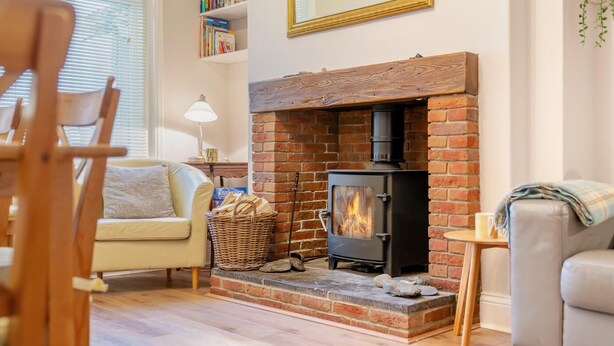 A cozy living room with a brick fireplace, a sofa, a small table, and a bookshelf. - 5 Bed in Runswick Bay (oc-wa817) (Runswick Bay)