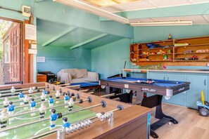 A room with a foosball table, a pool table, and shelves with toys and games. - 5 Bed in Runswick Bay (oc-wa817) (Runswick Bay)