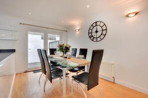 A modern dining area with a glass table, black chairs, and a wall-mounted clock. - 2 Bed in Porthleven (oc-p00866) (Porthleven)