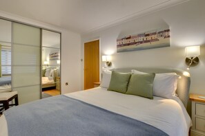 A bedroom with a bed, a wardrobe, a painting, and two wall-mounted lamps. - 2 Bed in Porthleven (oc-p00866) (Porthleven)