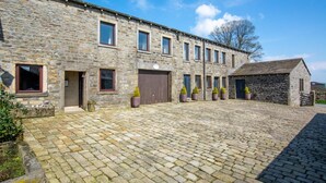 A stone building with multiple windows and doors, a cobblestone courtyard, and potted plants. - 2 Bed in Cowling (oc-ds239) (Cowling)