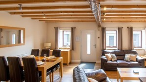 A spacious living area with a wooden ceiling, a dining table with chairs, a sofa, and a large mirror. - 2 Bed in Cowling (oc-ds239) (Cowling)