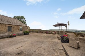 A courtyard with stone walls, benches, and potted plants.