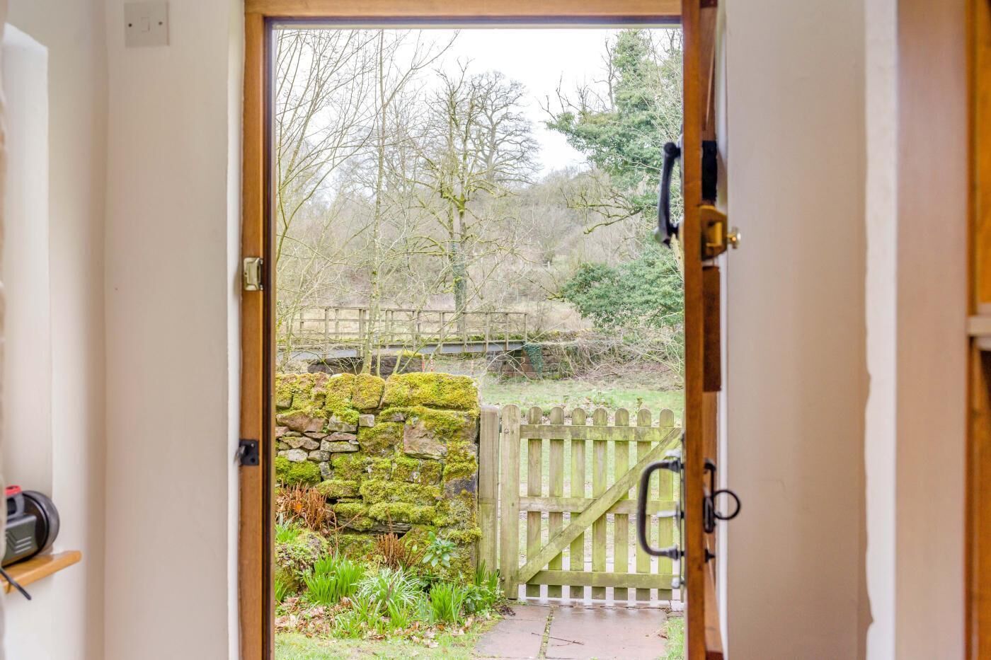A wooden door leading to a stone wall and a wooden gate.