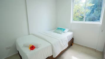 A single bed with white bedding, a pillow, and a decorative flower.
