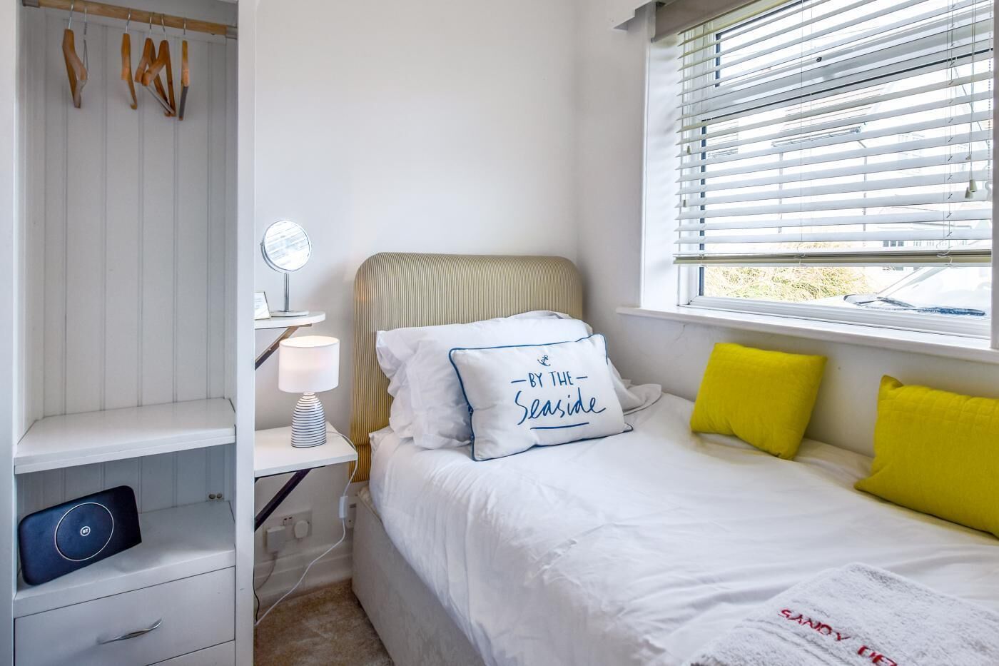 Une chambre à coucher avec un lit, une table de chevet, une lampe et une fenêtre avec des stores.