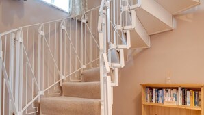 Un escalier en colimaçon avec des marches recouvertes d’une moquette beige et des rampes en métal blanc.