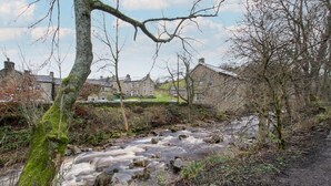 A river flowing through a rural area with stone walls and trees.