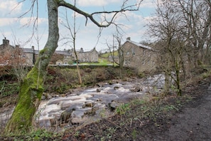 A river flowing through a rural area with stone walls and trees.