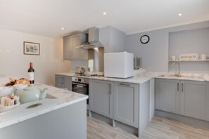 A modern kitchen with grey cabinets, a white countertop, a built-in oven, and a microwave.