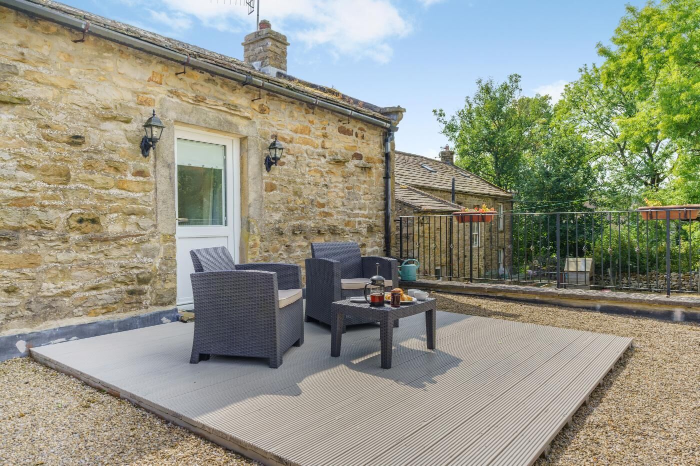 Un bâtiment en pierre doté d’un patio aménagé avec du mobilier d’extérieur et une table sur laquelle sont disposés divers objets.