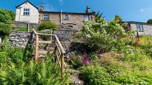 Une maison en pierre avec un escalier en bois menant à un mur de pierre.