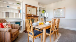 A dining area with a wooden table, chairs, and a mirror above it. - 3 Bed in Whitby (oc-r565) (Robin Hood's Bay)