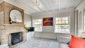 A living room with a fireplace, a sofa, a TV, and a large window. - 2 Bed in Whitby (oc-wa032) (Grosmont)