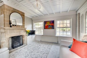A living room with a fireplace, a sofa, a TV, and a large window. - 2 Bed in Whitby (oc-wa032) (Grosmont)