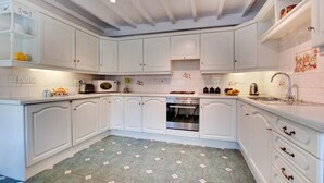 A kitchen with white cabinets, a microwave, oven, and a sink. - 2 Bed in Whitby (oc-wa032) (Grosmont)