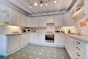 A kitchen with white cabinets, a microwave, oven, and a sink. - 2 Bed in Whitby (oc-wa032) (Grosmont)