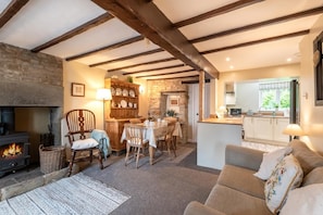 A cozy living room with a fireplace, wooden furniture, and a kitchen area with a window. - 2 Bed in Buxton (oc-dcthr) (Windmill)