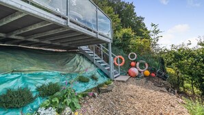 Un espace extérieur abrité, doté d’un escalier menant à une structure entièrement vitrée.