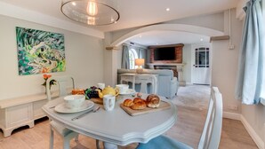 A dining area with a table set for breakfast, a fireplace, and a TV in the background. - 1 Bed in Whitby (oc-wa031) (Grosmont)