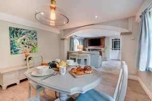Ein Essbereich mit einem für das Fr ühstück gedeckten Tisch, einem Kamin und einem Fernseher im Hintergrund.