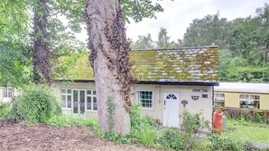 A small building with a moss-covered roof, surrounded by trees and vegetation. - 1 Bed in Whitby (oc-wa031) (Grosmont)
