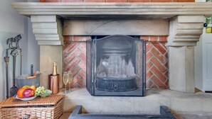 A fireplace with a screen, a brick wall, and a flat-screen TV above it. - 1 Bed in Whitby (oc-wa031) (Grosmont)