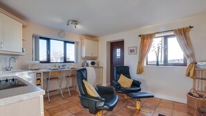 A compact kitchen with a sink, stove, and microwave. There are two chairs with cushions and a dining table. The room has a large window with curtains and a door with a glass panel. - 1 Bed in Chesterfield (oc-dcelm) (England)