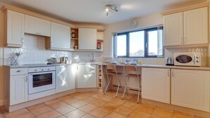 A kitchen with white cabinets, a stove, a microwave, and a window providing natural light. - 1 Bed in Chesterfield (oc-dcelm) (England)