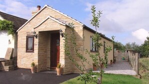 A small stone house with a wooden door and windows, surrounded by a gravel path and a grassy area. - 1 Bed in Chesterfield (oc-dcelm) (England)