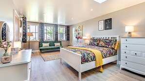 Ein modernes Schlafzimmer mit einem Bett, einem grünen Sofa, einer weißen Kommode und einem Oberlicht.