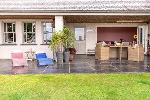 Een overdekt buitengebied met terras, zitplaatsen en potplanten.