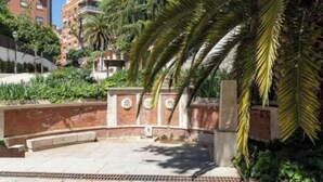 A courtyard with a brick wall, palm trees, and a building in the background. - AR Movistar Arena/Wizink centrally located and modern floor (Madrid)